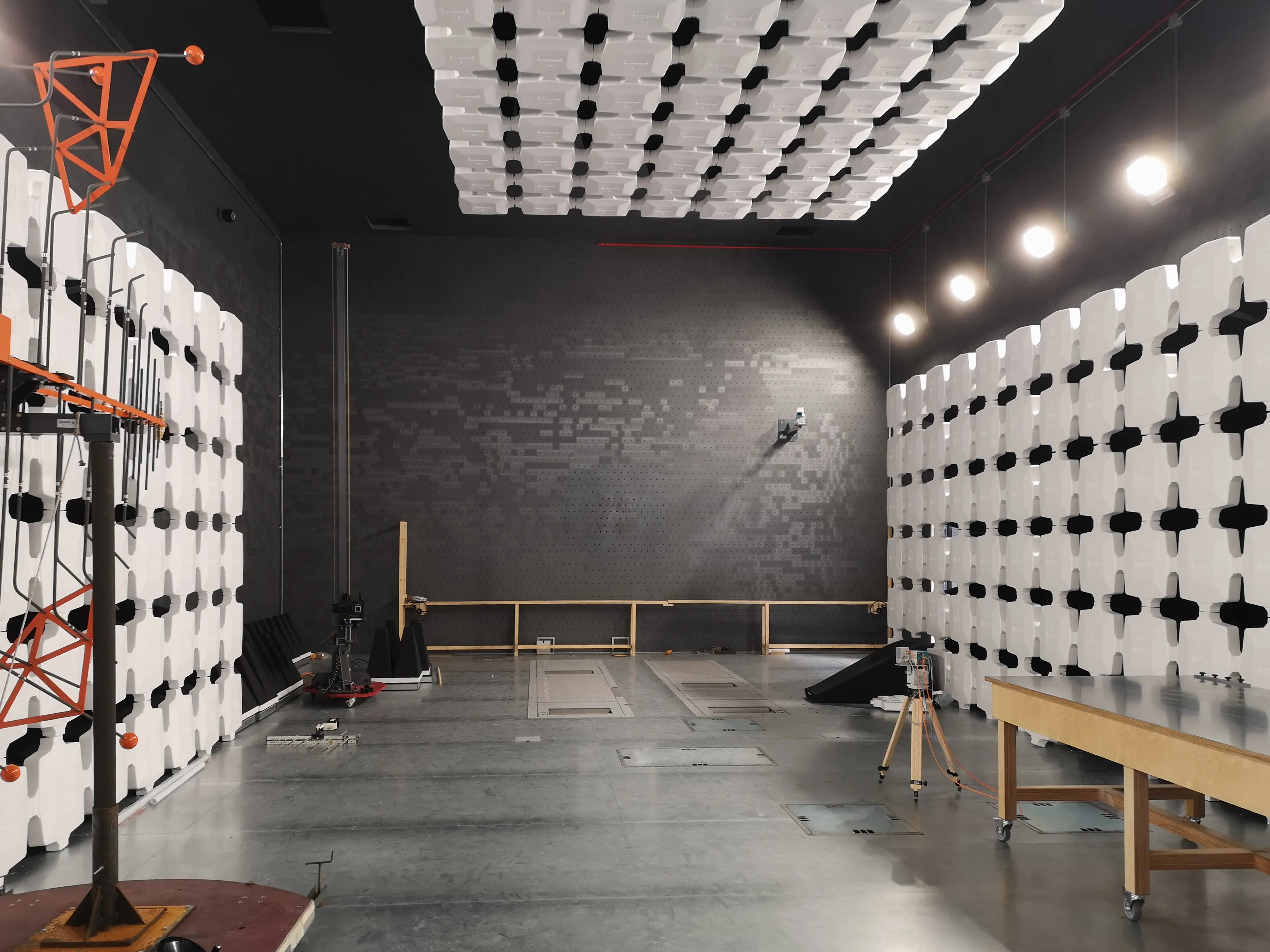 image of an interior view of a 10-meter EMC anechoic chamber, showcasing the specialized antenna setup used for electromagnetic compatibility testing. The room is lined with pyramidal absorbers for precise RF as part of MIL-STD-461 testing